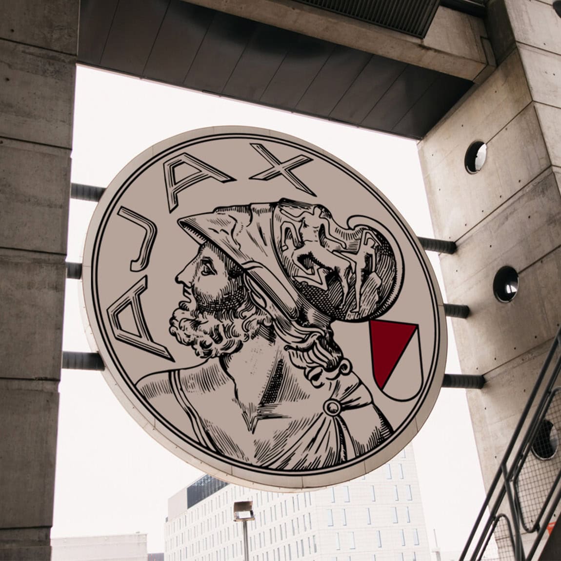 Large circular JAX signboard featuring a detailed illustration of a bearded man with a helmet, mounted on a concrete building exterior in a cityscape.