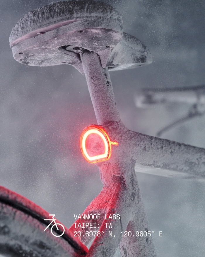 Frosty Bicycle in Snowy Landscape Close-up of a bicycle frame covered in snow with a red LED light on the frame, set against a snowy background, highlighting winter cycling.